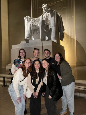 A group of students standing in front of the Lincoln Memorial at night.