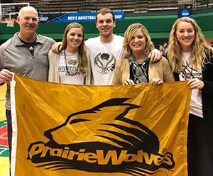Cook family behind a Prairie Wolves flag
