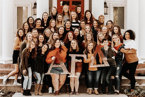 Large group of women posing in front of the AGD house.