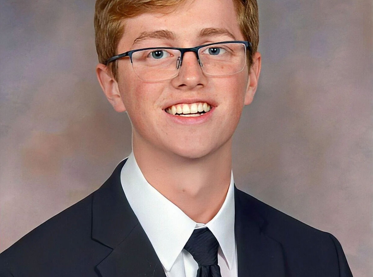 Kyle Goodban wearing glasses and a tie smiles.