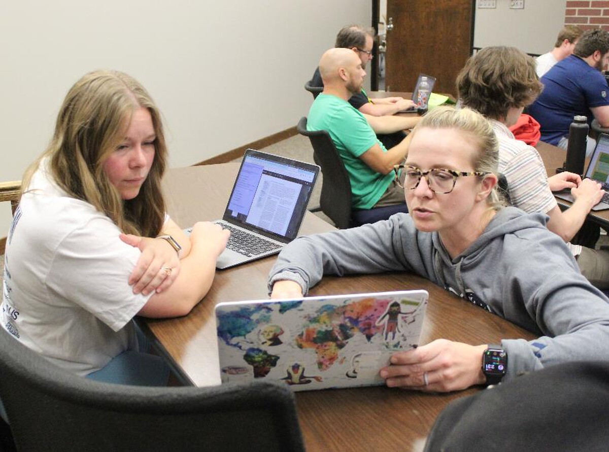 Students at a table looking at computers.
