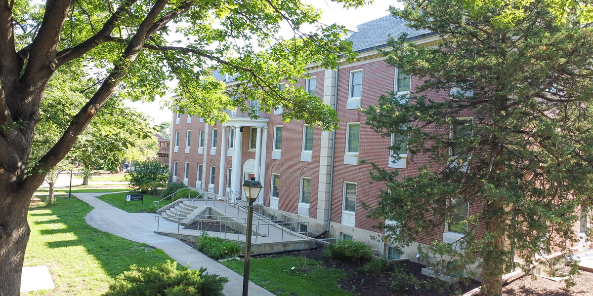 View of the east side of Johnson hall with trees in the foreground.