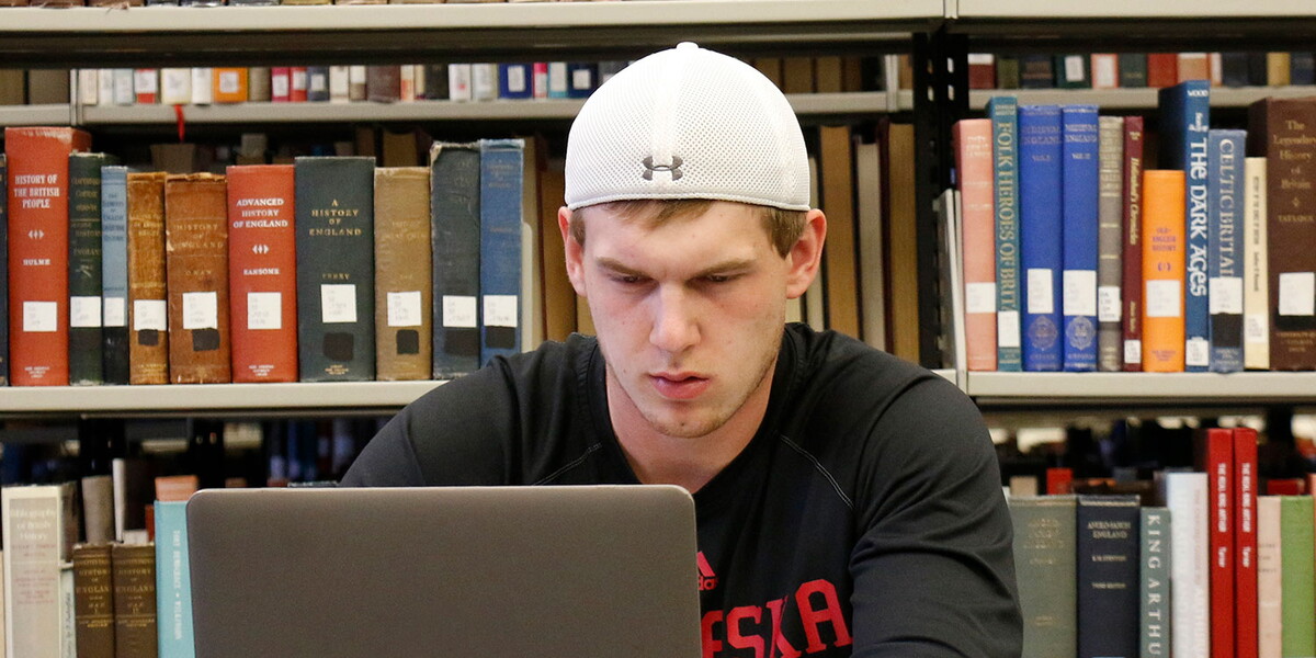 Male student in the library on a laptop