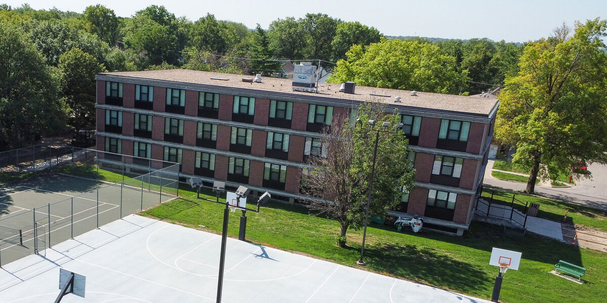 Aerial view of Plainsman Hall with a tennis and basketball court in the foreground.