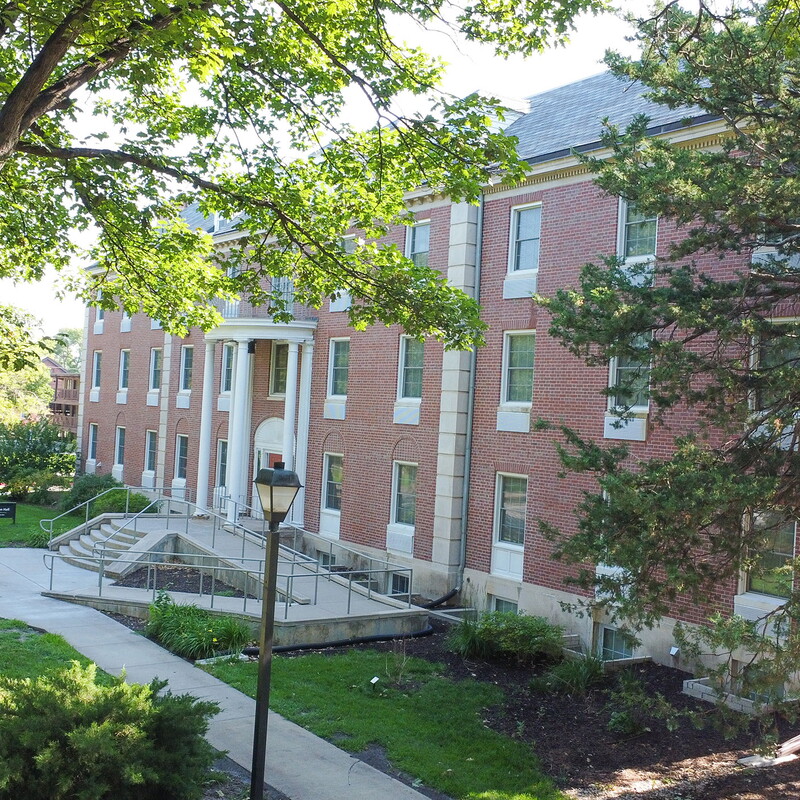 View of the east side of Johnson hall with trees in the foreground.