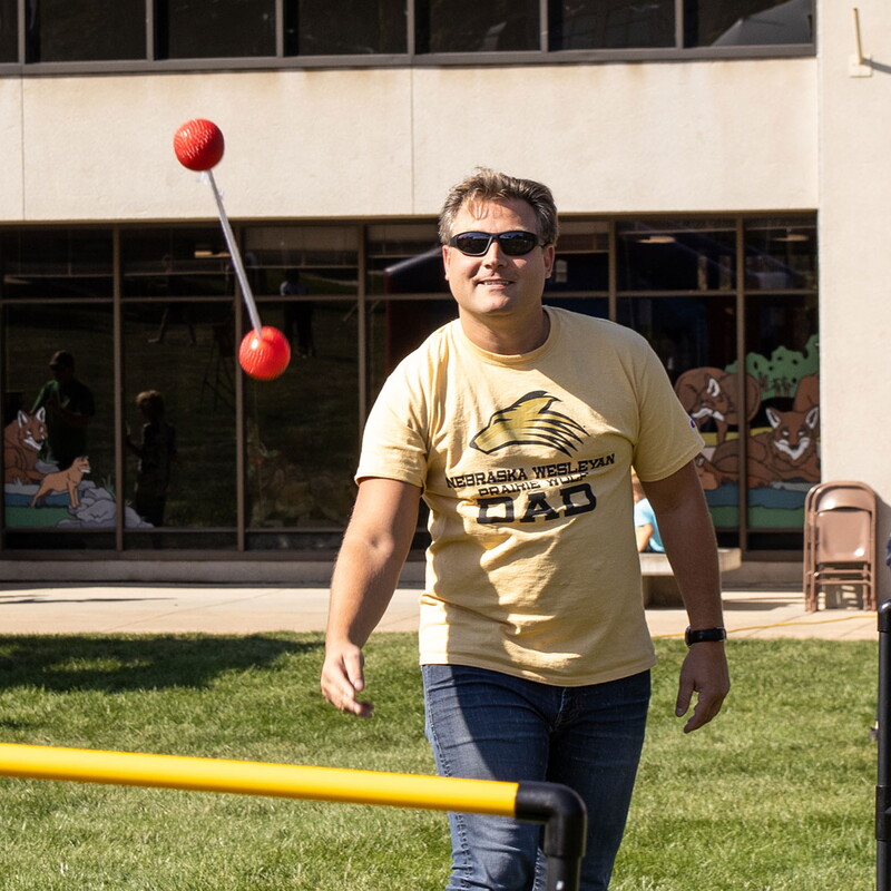 Man throwing a ladder ball wearing a t-shirt that says Prairie Wolf Dad