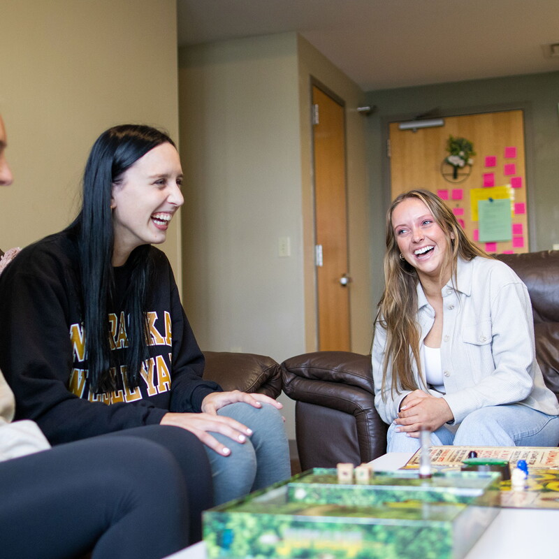 Four young women sitting around a coffee table playing a game.
