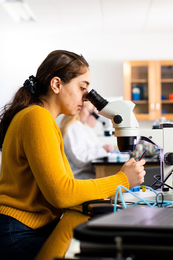 Female student looking through microscope.