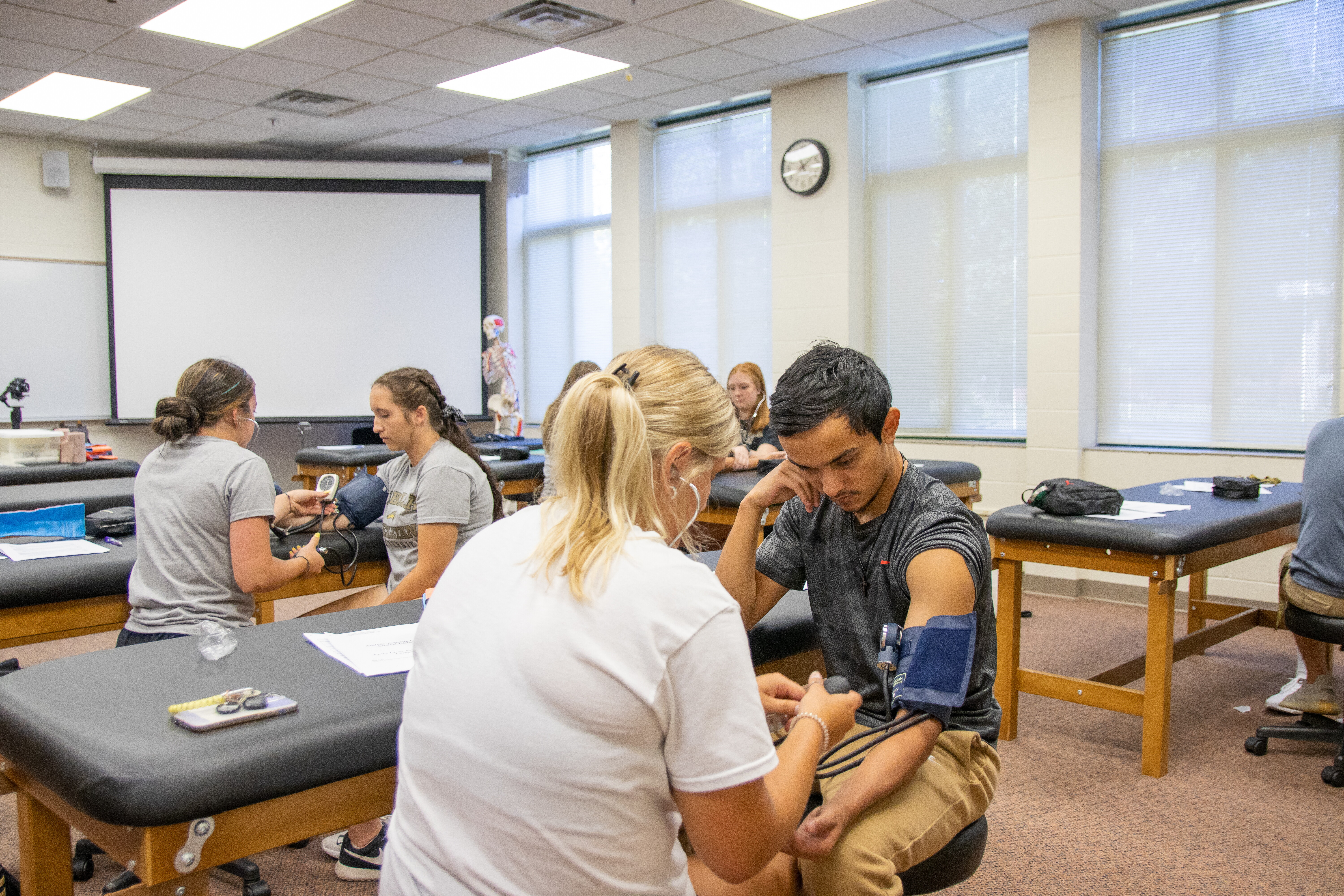 Students in a classroom paired up taking blood pressure.