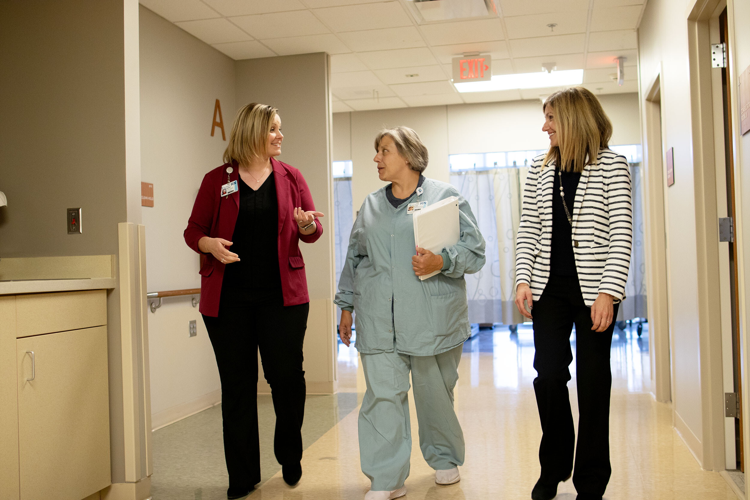 Three women walk down a hospital hallway.