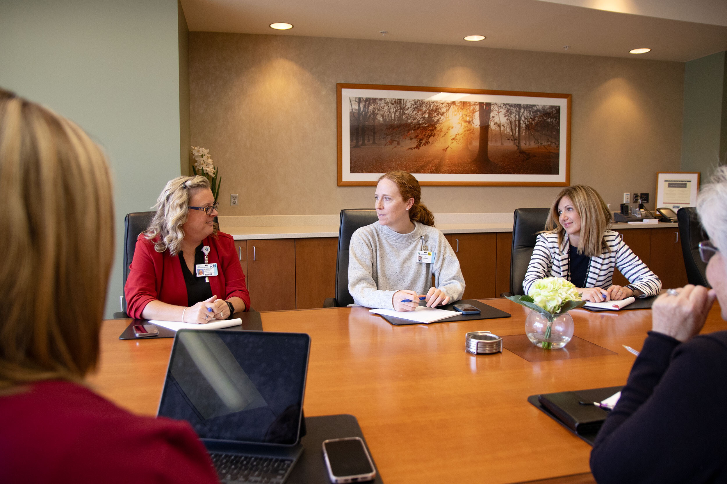 Five women sitting in a conference room having a meeting.