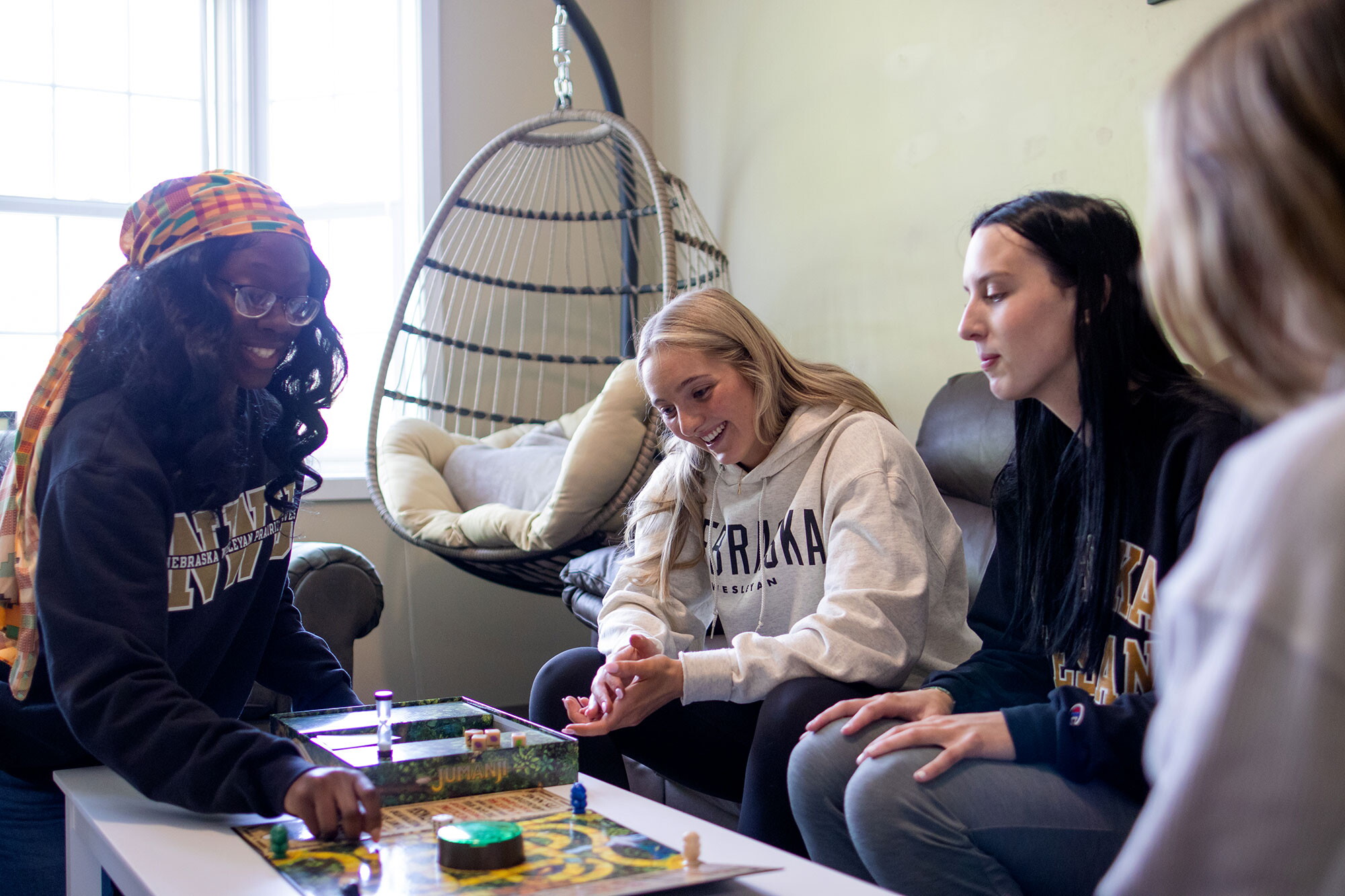 Four young women around a coffee table in a living room playing a game.