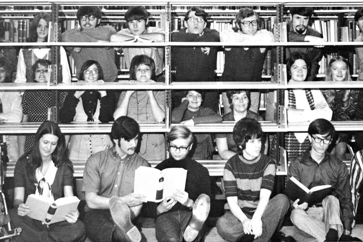 Photo dated 1971, students in front and behind book shelves in the library.