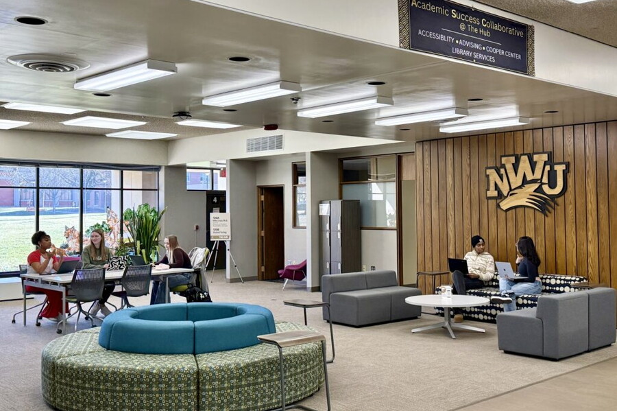 The first floor of the library has students sitting in spaces studying.