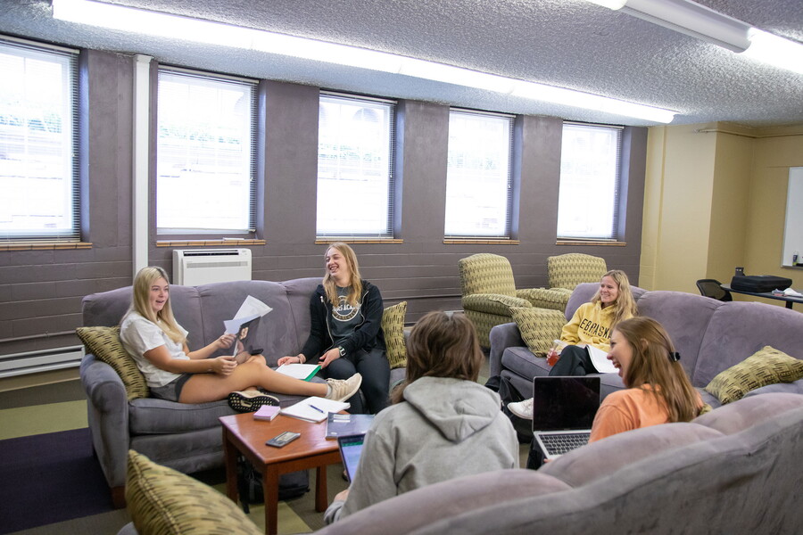 A group of female students sitting in a circle on couches in a common area in Johnson.