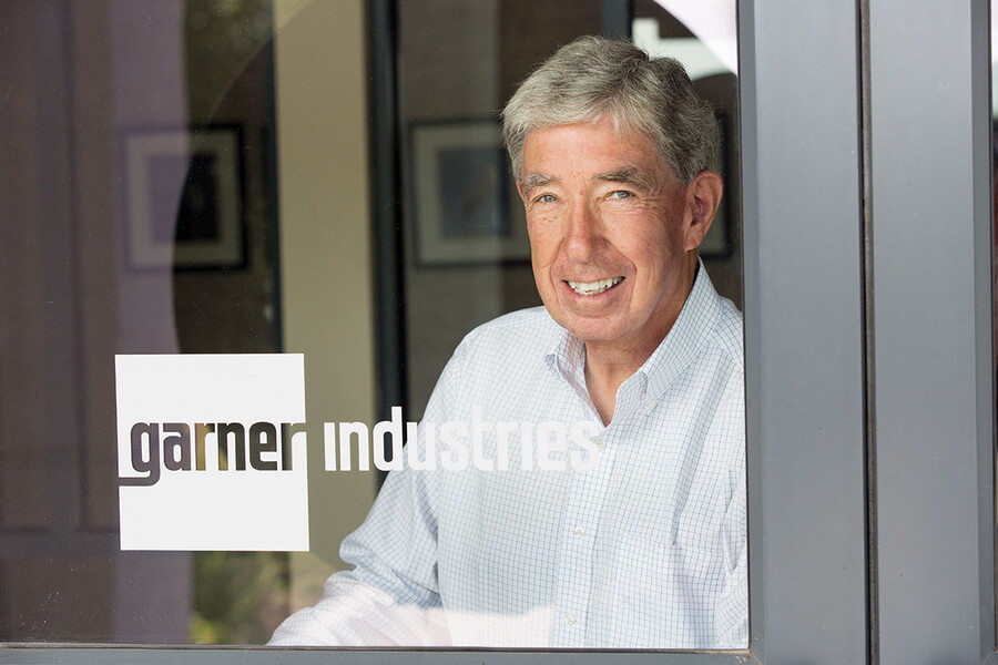 Head shot of Philip Mullin behind a glass door with a logo that says, Garner Industries.