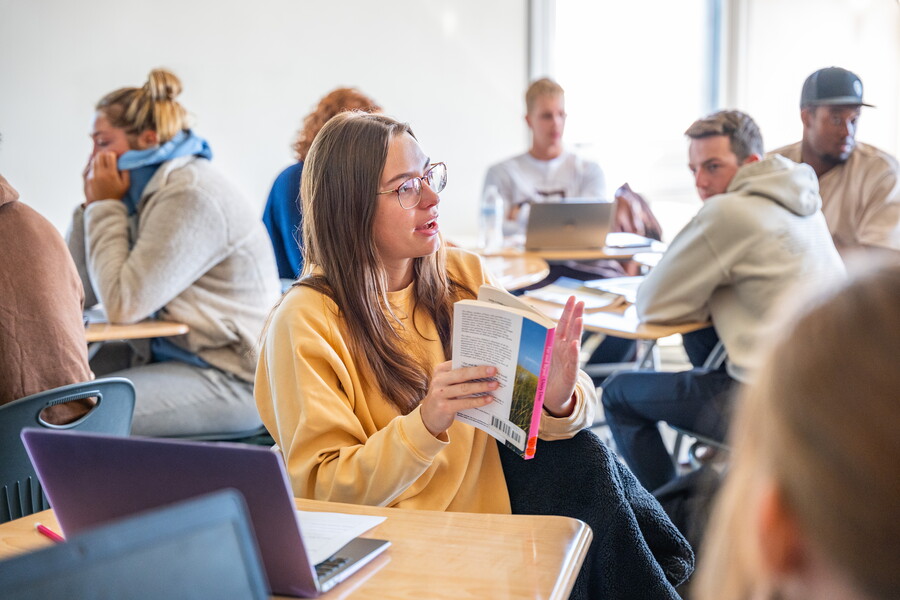 A student in a classroom talking to classmates.