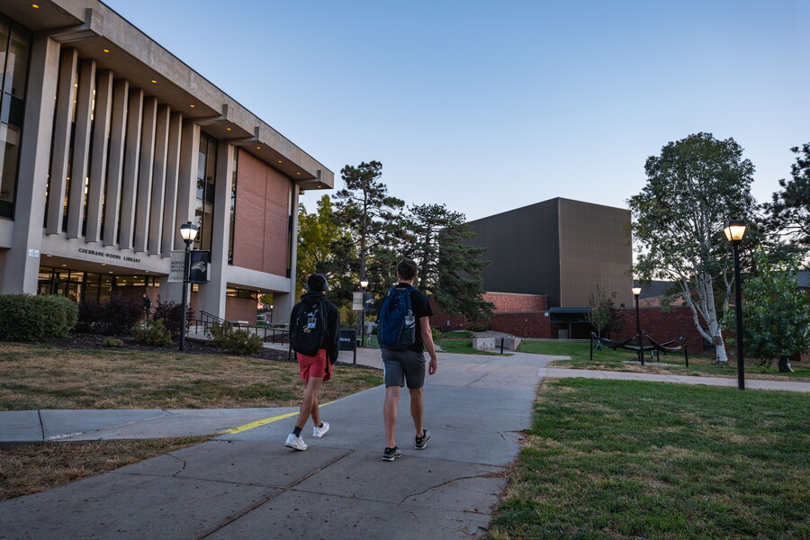 Two students walking at night in front of the library.