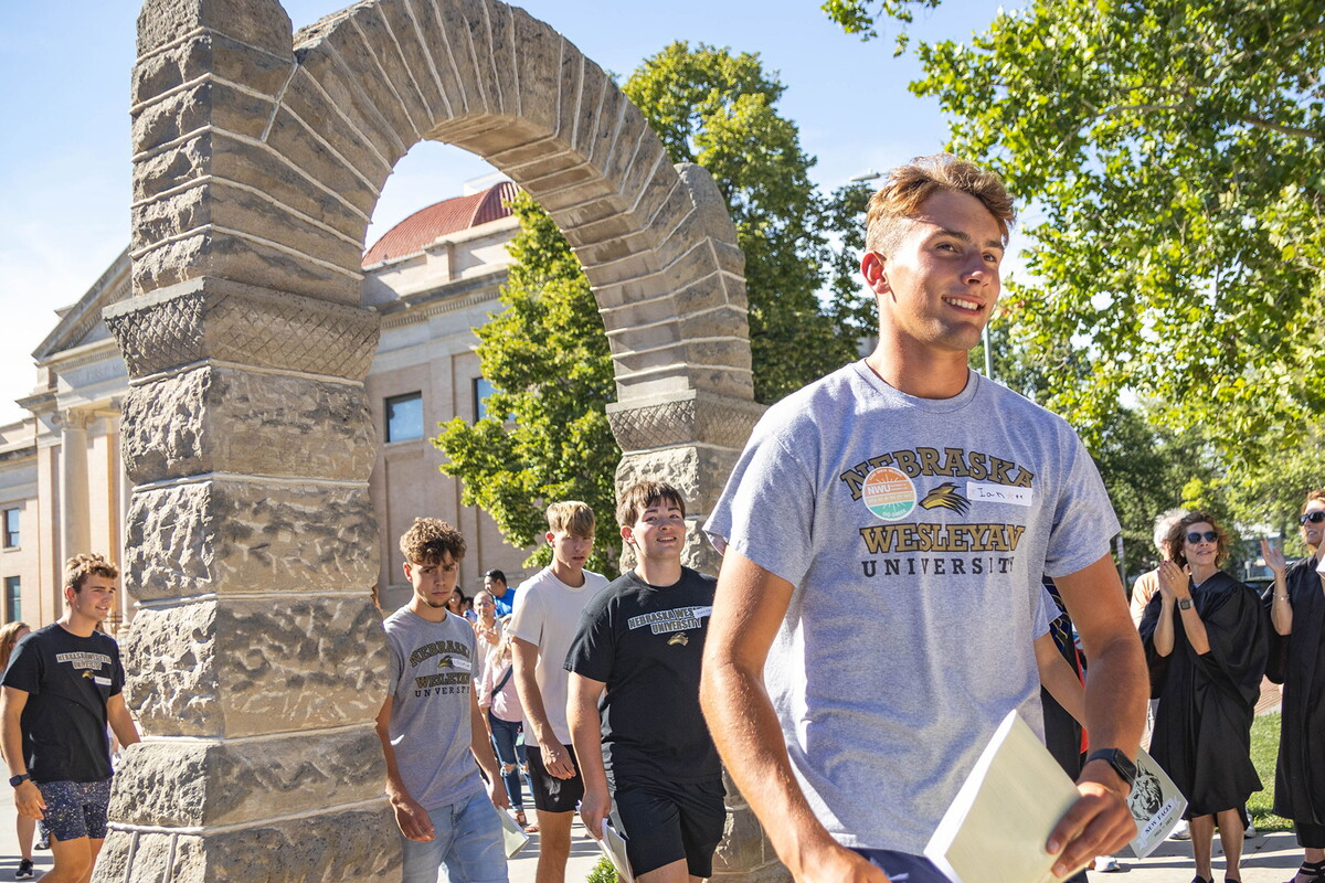 Students walk thru the stone arch with faculty, staff and parents cheering.