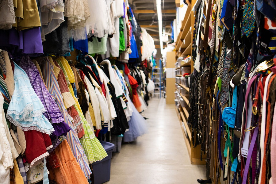 Looking down the aisle, two rows of costumes stacked on top of each other line both sides of the aisle.