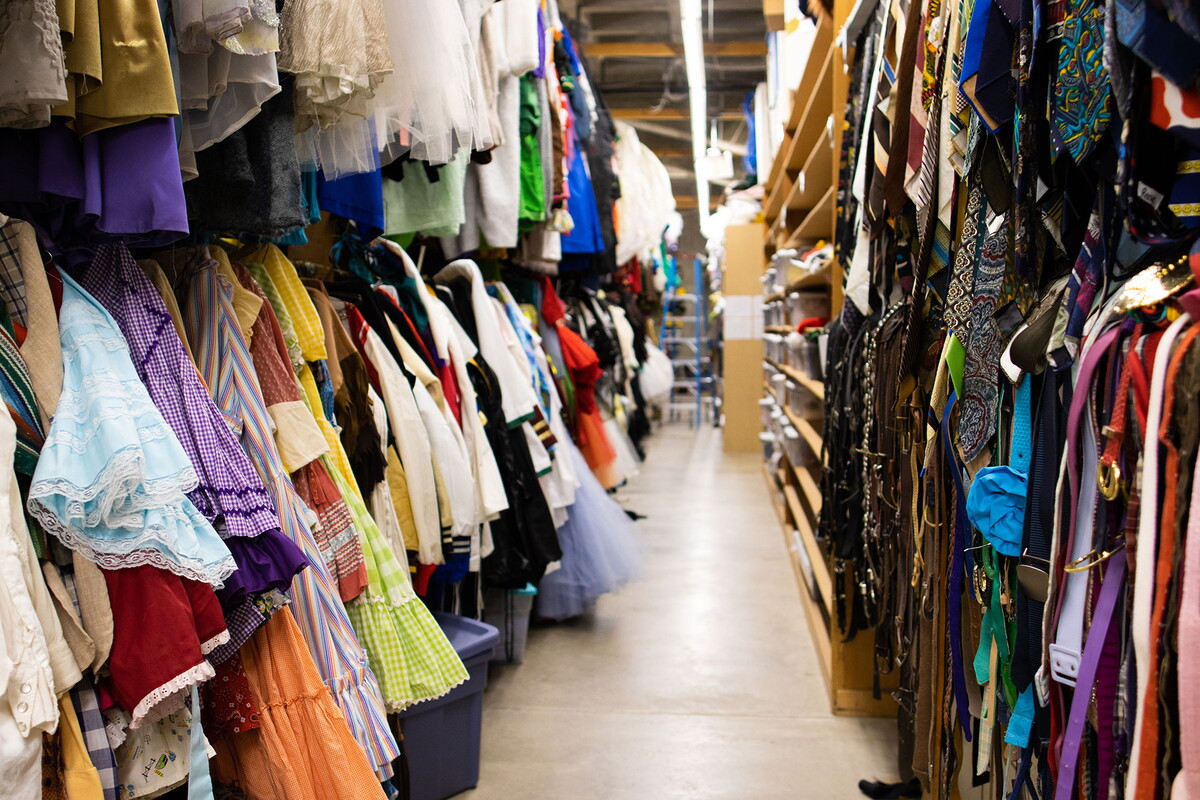 Looking down the aisle, two rows of costumes stacked on top of each other line both sides of the aisle.
