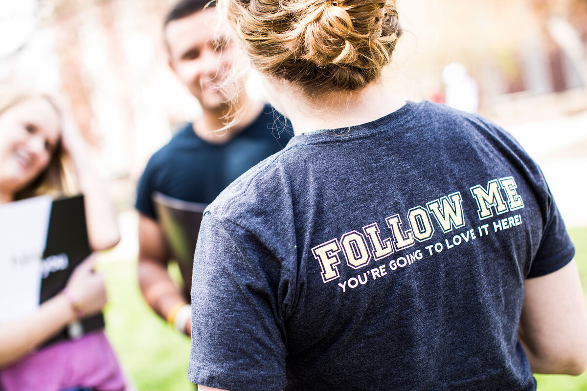 Woman with her back to the camera in a shirt that says, 'Follow Me'.