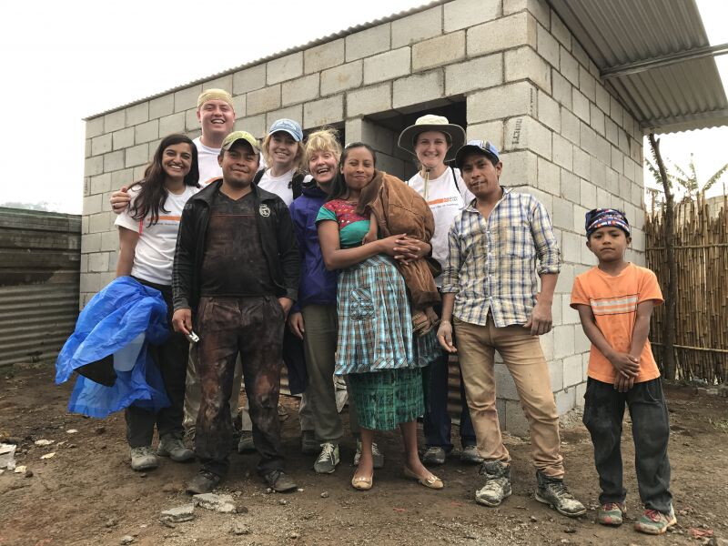 Students stand alongside the family that will live in the home they help build.