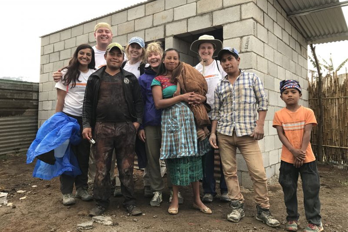 Students stand alongside the family that will live in the home they help build.