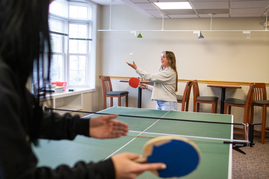 Young women playing ping pong in a common area of the suites.