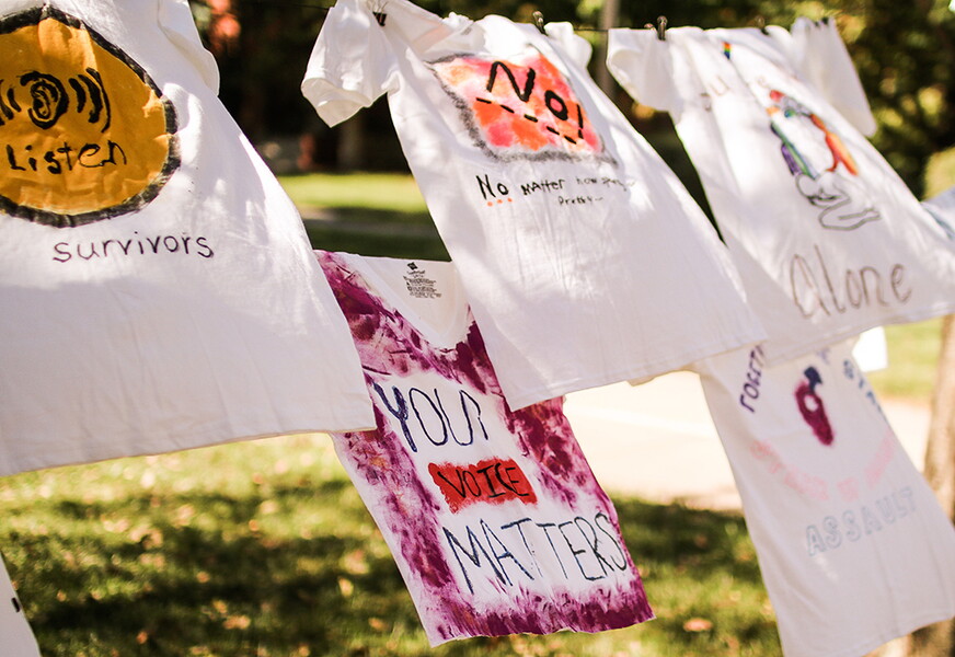 T-shirts hanging on a clothes line in front of the library with messages raising awareness to gender-based violence