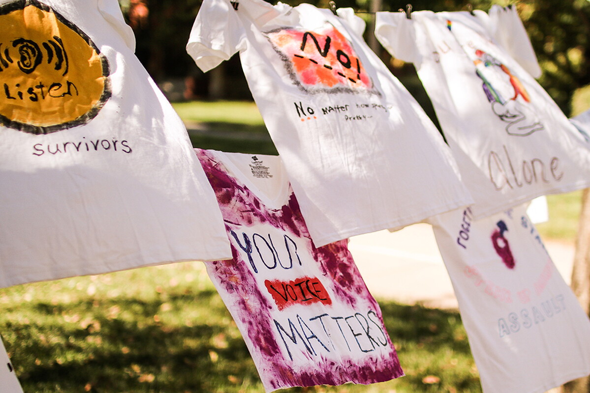 T-shirts hanging on a clothes line in front of the library with messages raising awareness to gender-based violence