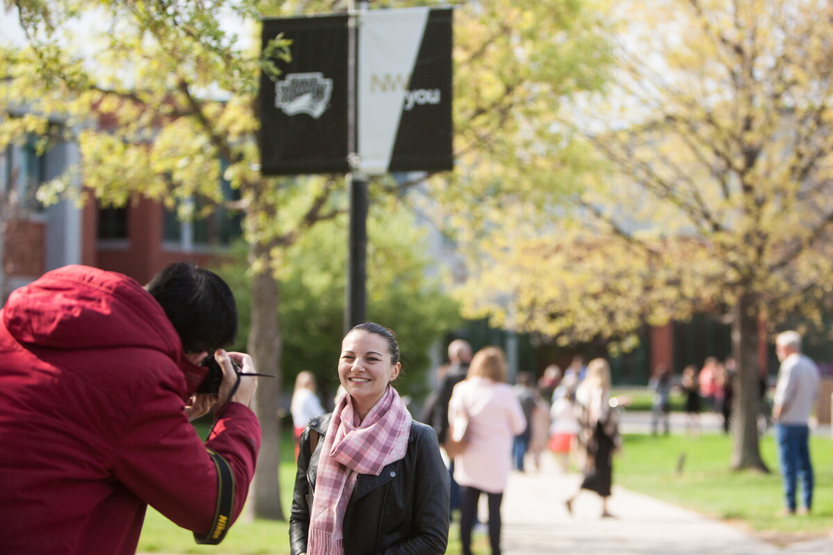 On a campus full of visitors, man stops to take a picture of a woman