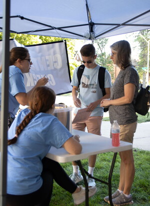 Two residential education staff members help a male first-year student and mother navigate the move -in process