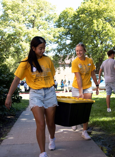 Two young women carry a tote into Johnson Hall.