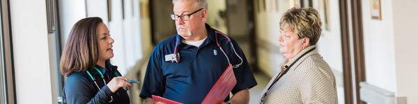 Three nurse administrators walk in a hospital hallway.