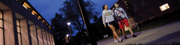 Two female students walking at night in front of a lit up Weary Center.