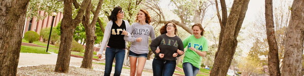 Alpha Gamma Delta sorority sisters linking arms walking on campus.