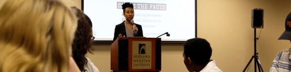 A female guest speaker behind a podium in front of an audience.