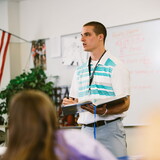 High school teacher standing and talking in front of the class.