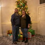 A couple standing in front of a Christmas tree. 